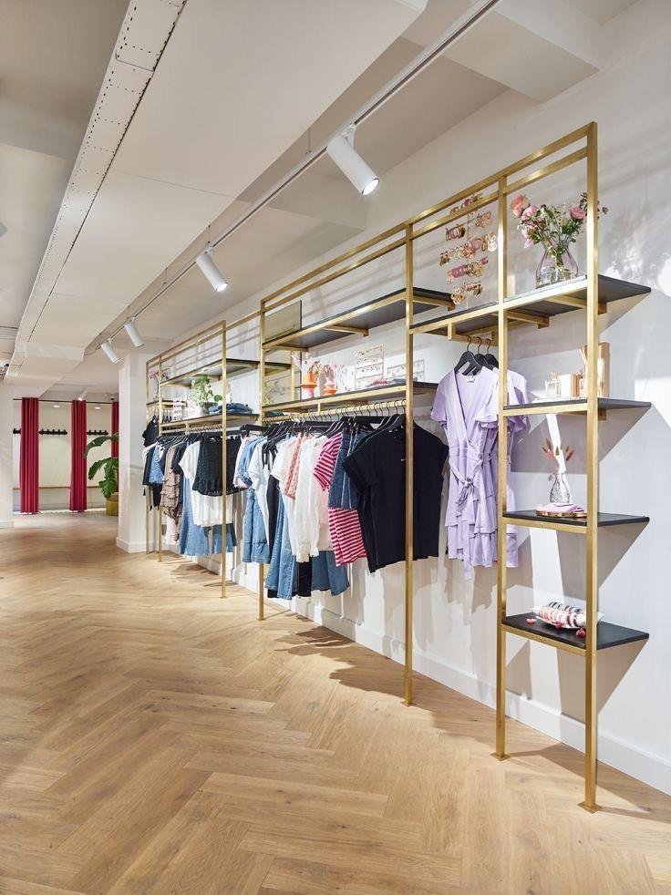 Tienda de ropa con rieles y entrepaños en acabado dorado